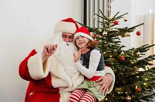 Der Weihnachtsmann winkt mit Kind in die Kamera